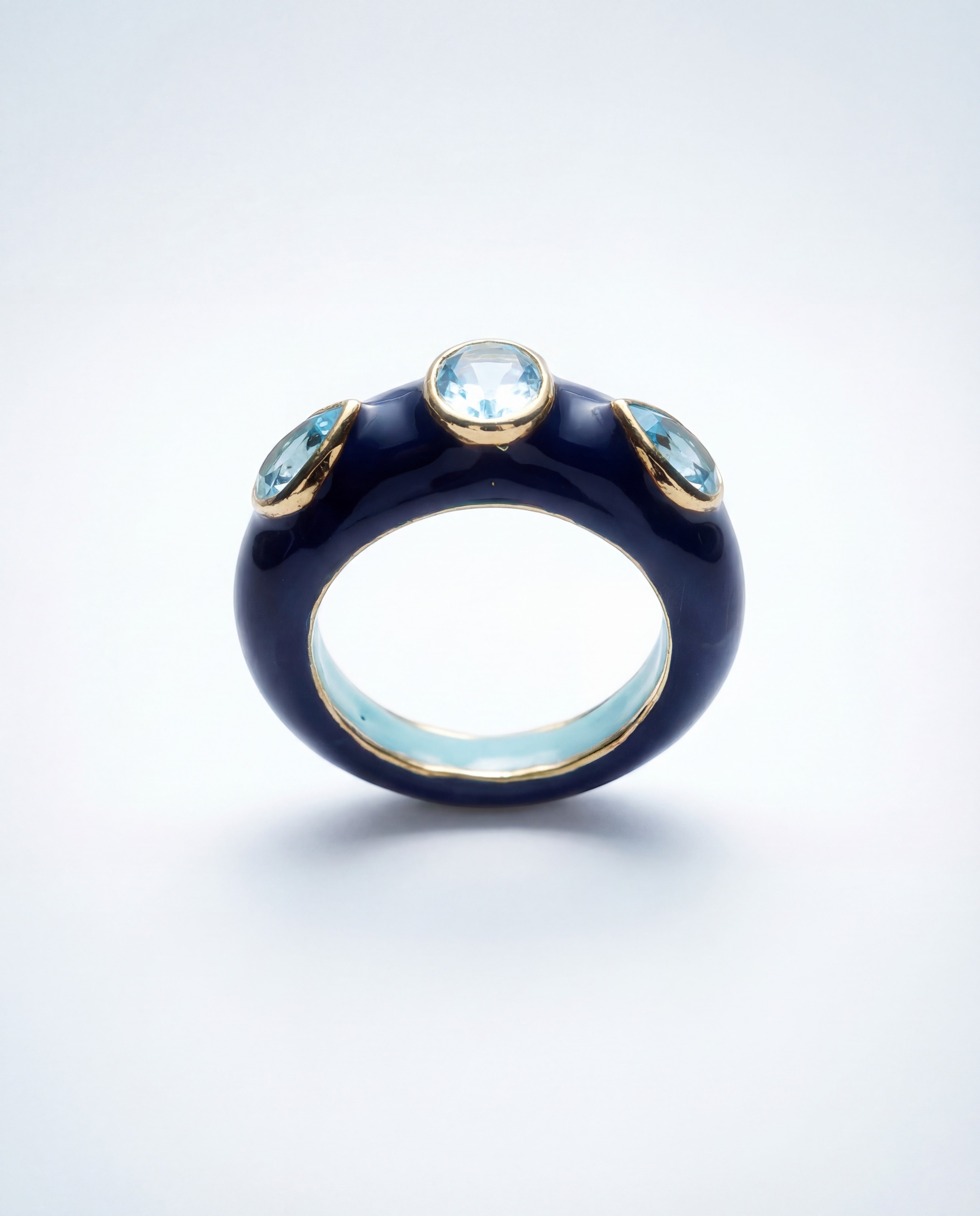 HEILI ROCK Callais ring with dark blue enamel band, gold setting, and three light blue gemstone cabochons.