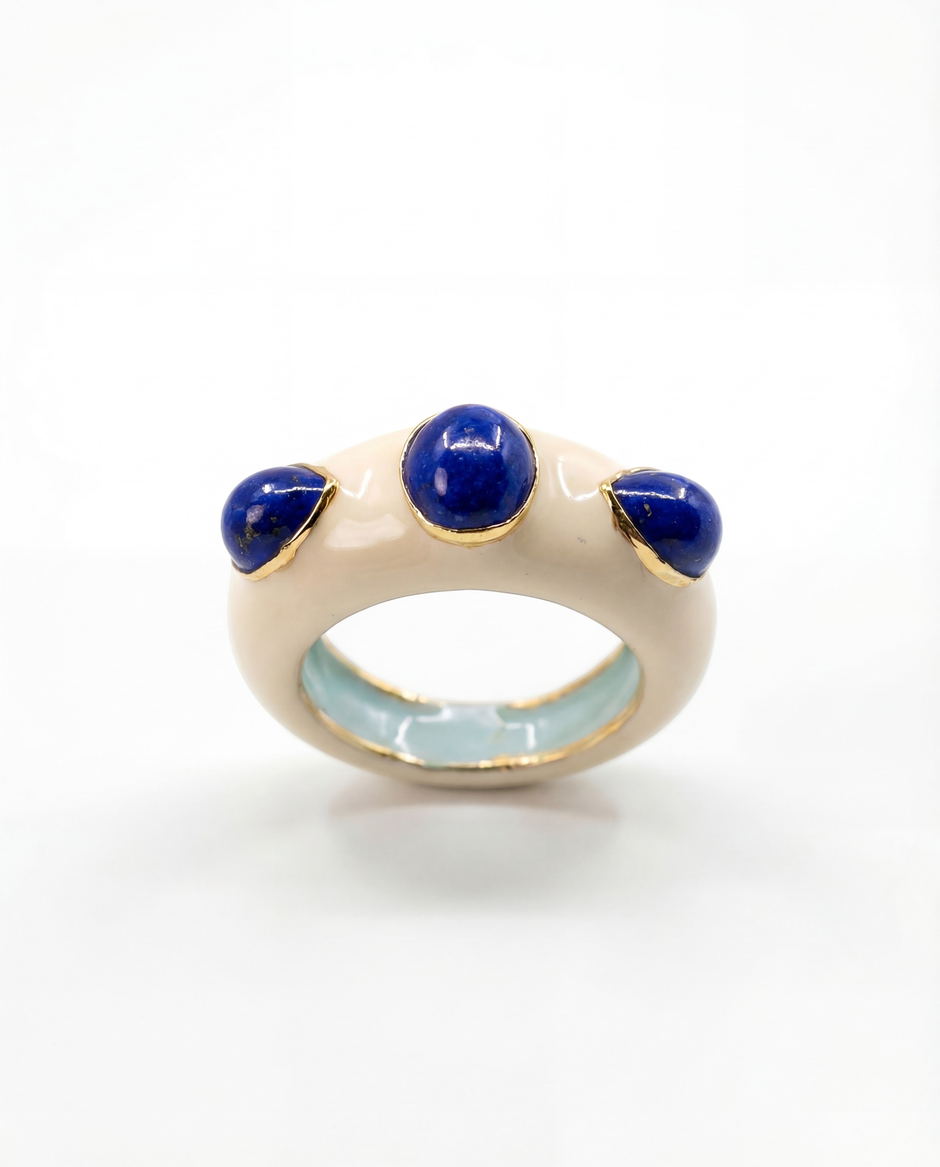 HEILI ROCK Callais ring with three blue lapis lazuli cabochons set in a cream enamel band with gold accents.